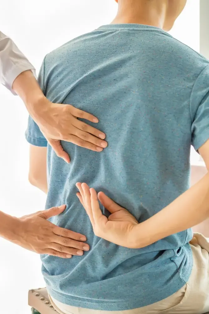 Clinician performing a hands-on examination of a patient's back