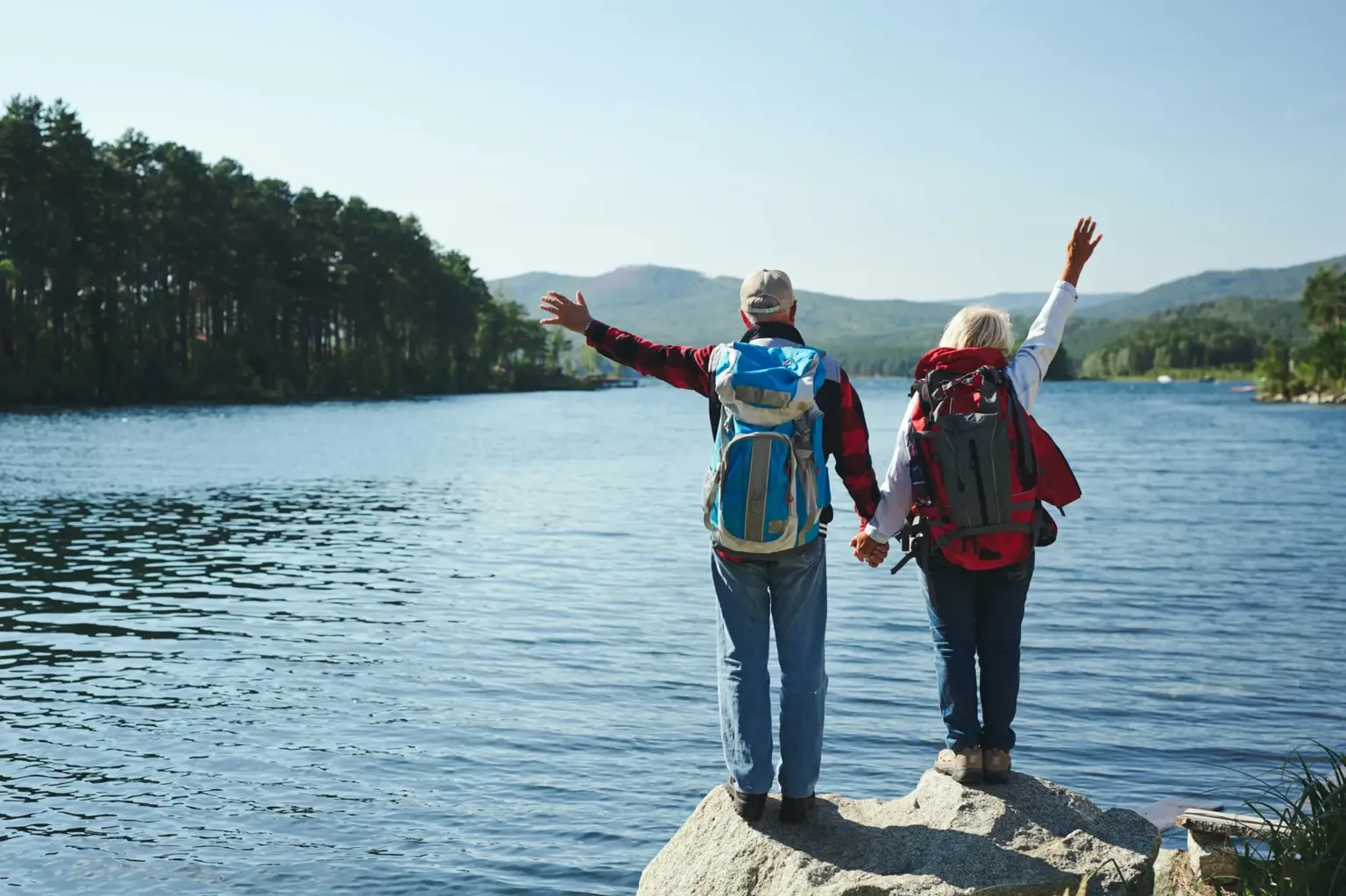 Older couple standing beside a mountain lake after a hike